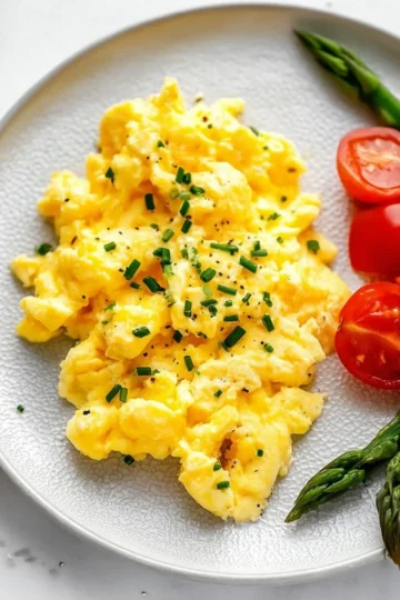 Plate of cottage cheese scrambled eggs topped with herbs