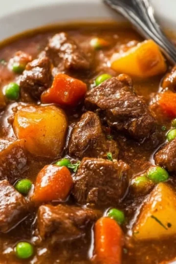 Bowl of easy crockpot beef stew with vegetables and herbs