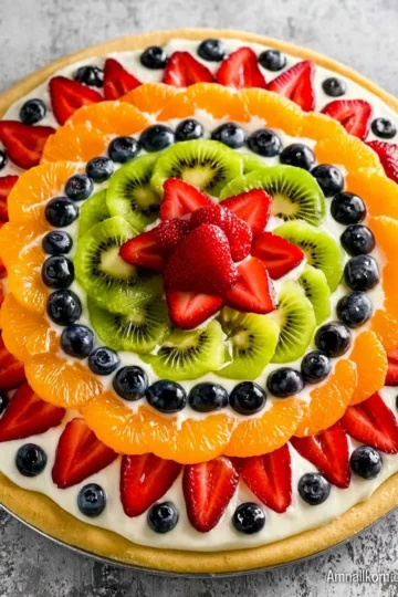 Fruit pizza topped with colorful fruits on a sugar cookie crust.