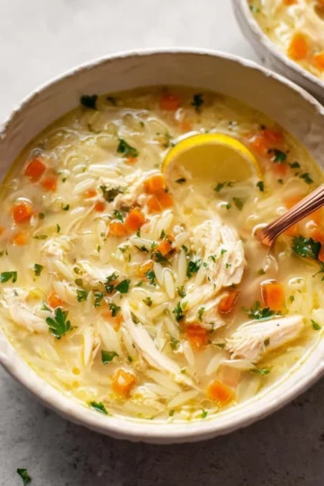 Bowl of lemon chicken orzo soup garnished with fresh herbs