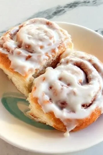 Delicious homemade cinnamon rolls topped with icing on a baking tray
