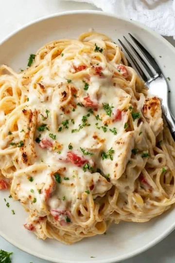 A bowl of Chicken Spaghetti with Rotel topped with cheese and herbs