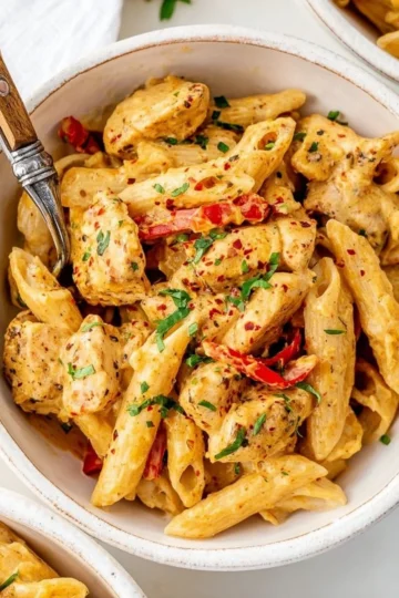 Delicious creamy Cajun Chicken Pasta garnished with herbs and spices.