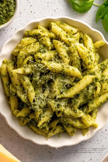 Creamy pesto pasta dish topped with fresh basil and pine nuts
