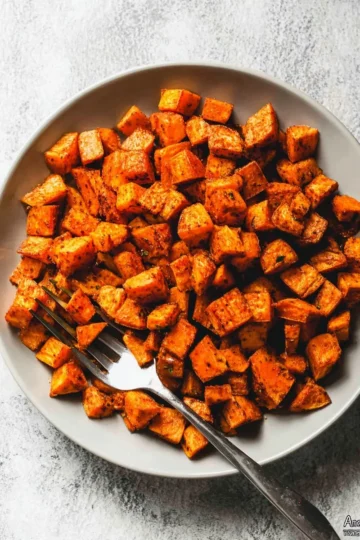 Crispy roasted sweet potatoes on a baking sheet, golden and delicious.