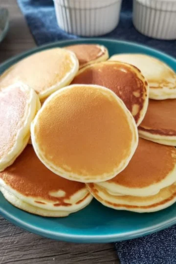 Plate of delicious mini pancakes topped with syrup and berries