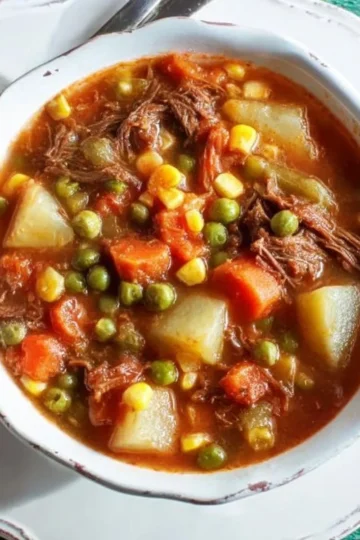 Delicious old-fashioned vegetable beef soup served in a bowl with fresh ingredients.