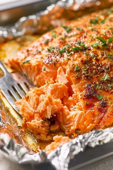 Perfectly oven baked salmon fillet on a plate with herbs and lemon