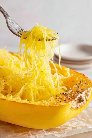 Roasted spaghetti squash with herbs and spices on a wooden plate