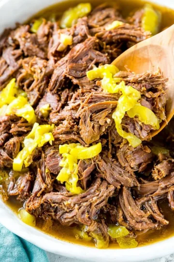 Delicious Slow Cooker Italian Beef served with fresh herbs and buns